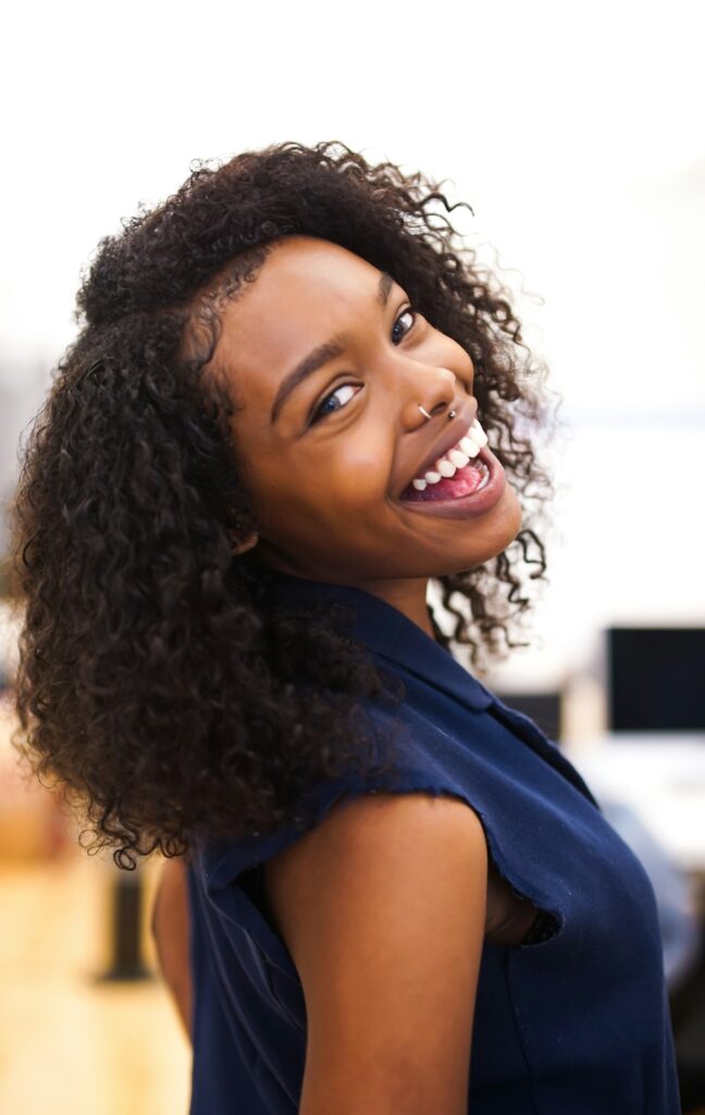 Woman with curly hair smiling over her shoulder